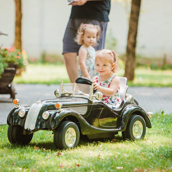 The little baby girl playing at car against green grass